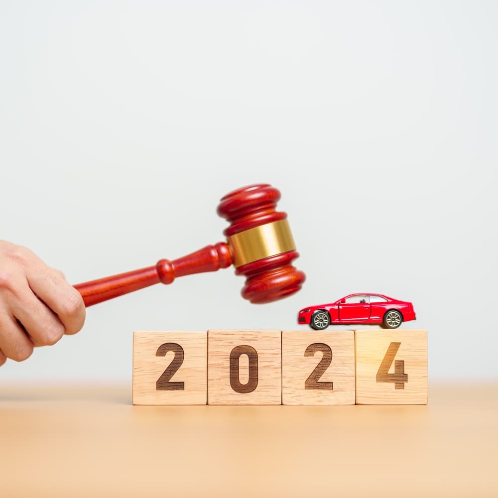 2024 Car Law and Insurance Concepts: Toy Car Models with a Judge's Gavel on a Courthouse Desk