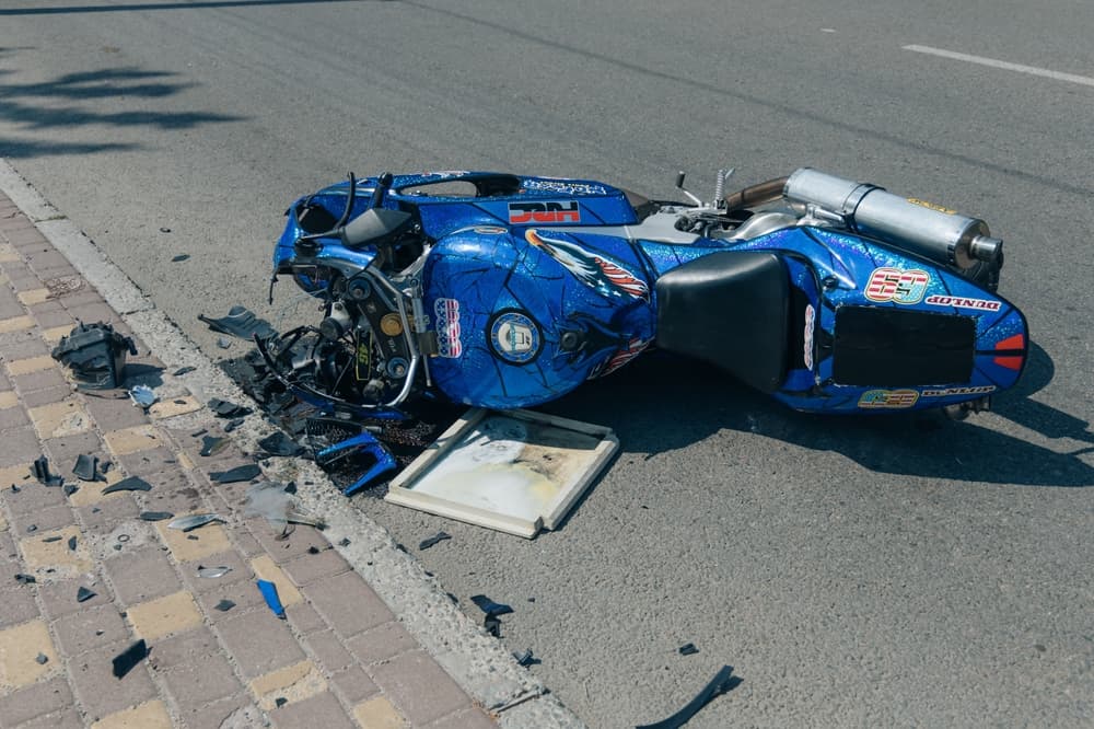 The motorcycle lies on the pavement after a traffic accident.